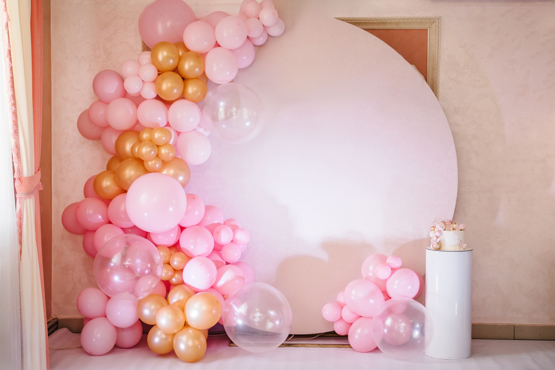 Arch decorated with pink, white and golden balloons. Trendy baptism cake for girl. Delicious reception at a birthday party. Photo wall decoration space or place for text. Celebration in El Paso.